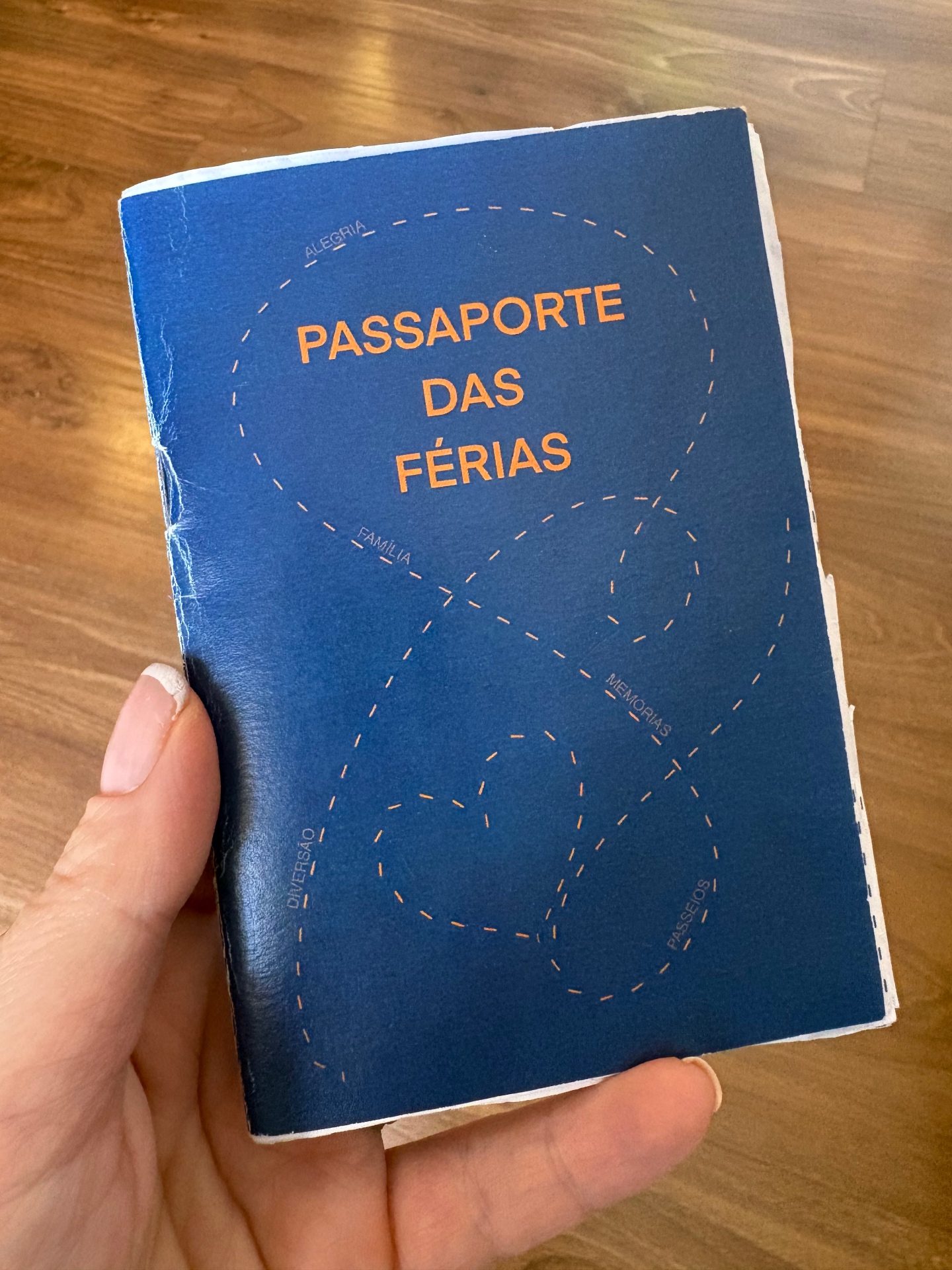Capa real do Passaporte das Férias em azul com detalhes em laranja